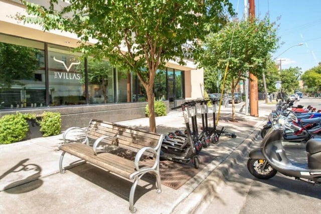 Wooden bench electric scooters and scooters exterior at Villas on 26th in Austin Student Accommodation