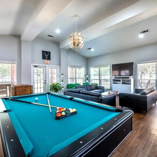 Pool table sofas and TV living room at Village Oaks Apartments in Waco Student Accommodation