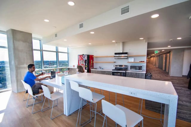 Man at laptop kitchen with soda machine kitchen at UnionWest Student Living in Orlando Student Accommodation