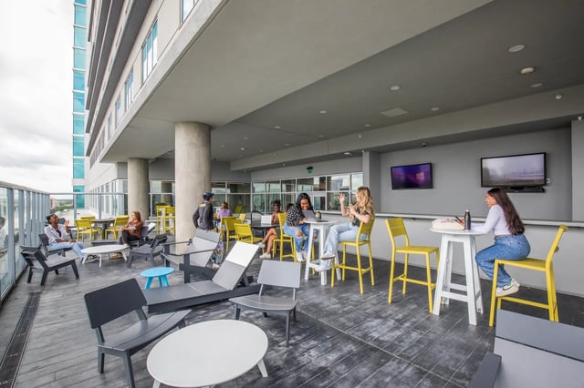 Students socialize at tables and lounge chairs exterior at UnionWest Student Living in Orlando Student Accommodation
