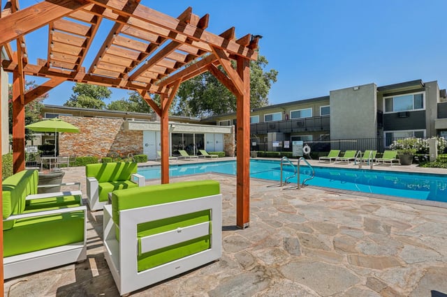 White seating with green cushions by pool exterior at The Spoke in Davis Student Accommodation
