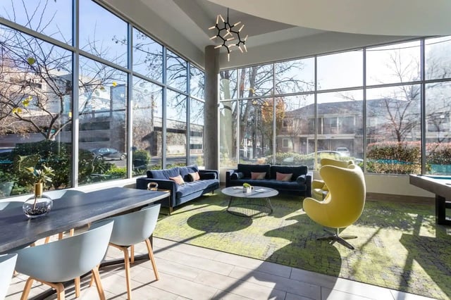 Blue sofas yellow chair dining table living area at The Soto in Eugene Student Accommodation