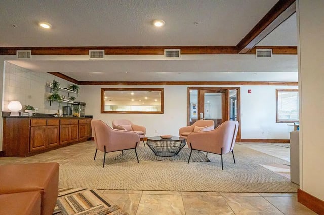 Pink chairs coffee table kitchen area living room at The Grove at Mankato in Mankato Student Accommodation
