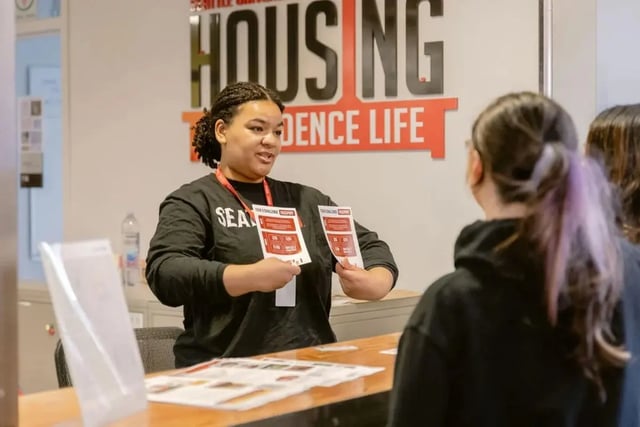 Staff member giving brochures at housing desk area at The Douglas - Student Housing Apartments in Seattle Student Accommodation