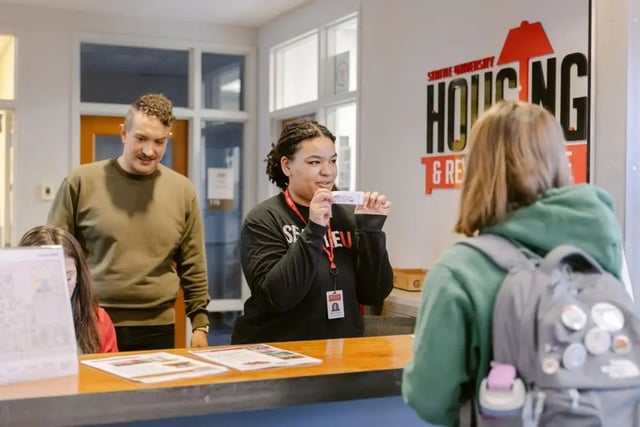 Staff member hands card to student at reception desk at The Douglas - Student Housing Apartments in Seattle Student Accommodation