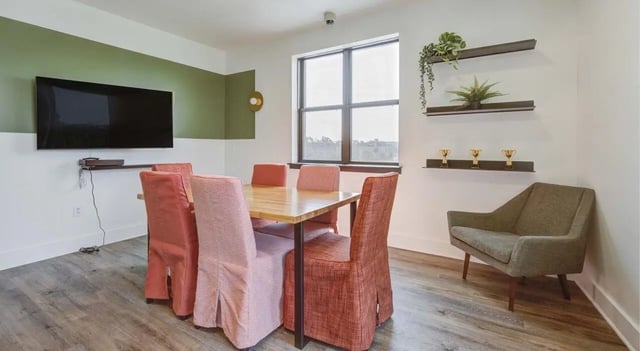 Table chairs TV on wall and armchair study area at The Varsity College Park in College Park Student Accommodation