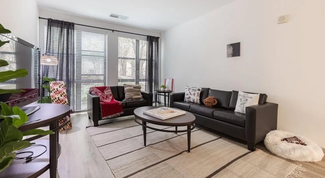 Two black couches oval coffee table rug living room at The Varsity College Park in College Park Student Accommodation