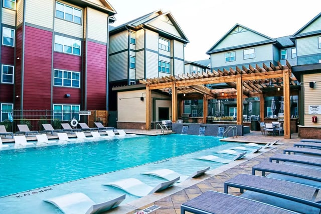 Apartment buildings surrounding sparkling blue swimming pool exterior at The Bloc in Lubbock Student Accommodation