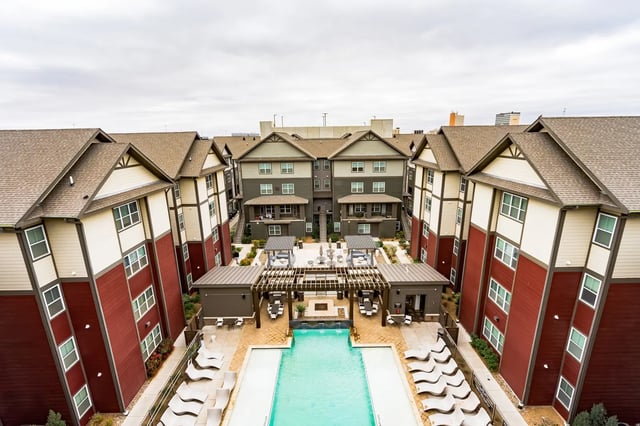 Apartment buildings surrounding a pool and seating area exterior at The Bloc in Lubbock Student Accommodation