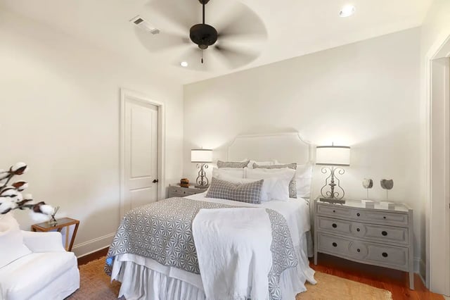 Bed with patterned quilt ceiling fan white armchair bedroom at The Cottages at Hooper Hollow in Oxford Student Accommodation