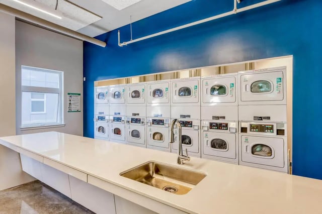 White countertop sink and stacked washers laundry room at Stateside in Bellingham Student Accommodation