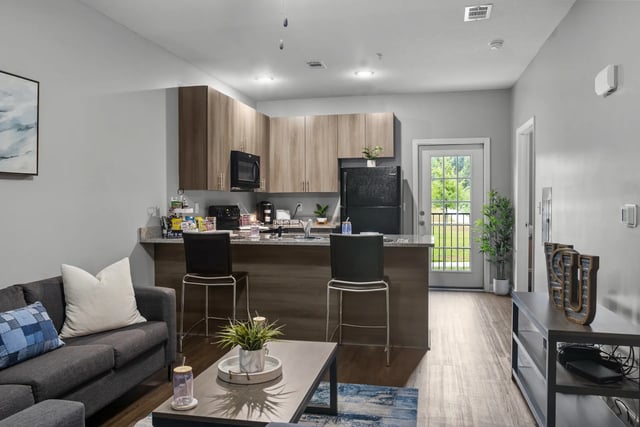 Sofa island kitchen bar stools coffee table living room at Remerton Mill Apartments in Valdosta Student Accommodation