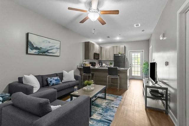 Gray sectional couch coffee table painting kitchen living room at Remerton Mill Apartments in Valdosta Student Accommodation