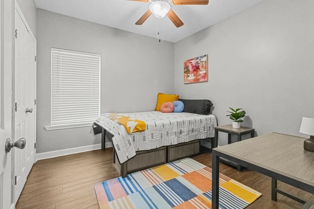 Bed with drawers desk and colorful rug bedroom at Remerton Mill Apartments in Valdosta Student Accommodation