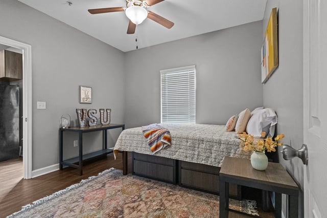 Bed ceiling fan art rug and desk Bedroom at Remerton Mill Apartments in Valdosta Student Accommodation