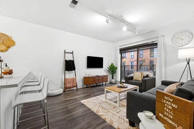 Bar with stools TV ladder and sofa living room at Slate at 901 in Knoxville Student Accommodation