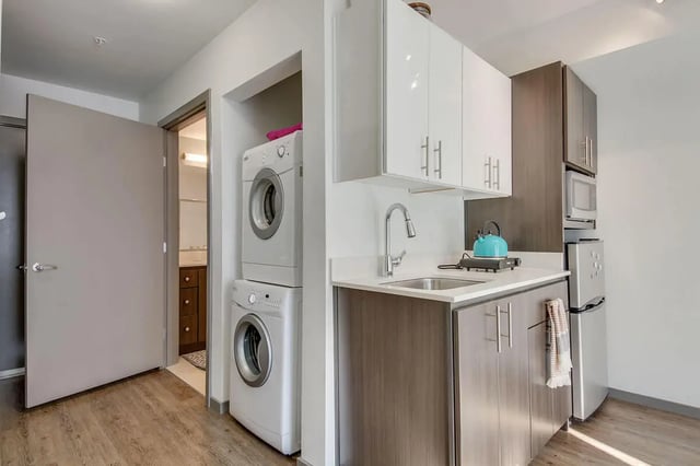 Stacked washer dryer sink microwave refrigerator kitchen at NORA Apartments in Seattle Student Accommodation