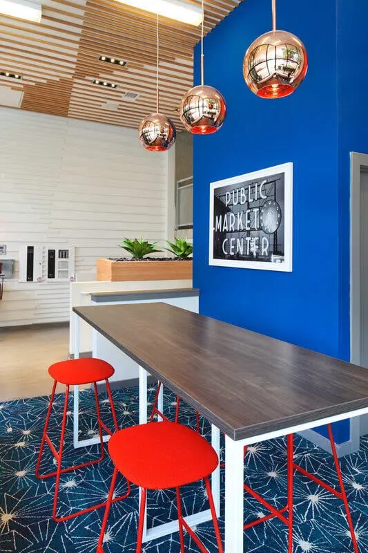 Wooden table with red stools and artwork area at NORA Apartments in Seattle Student Accommodation