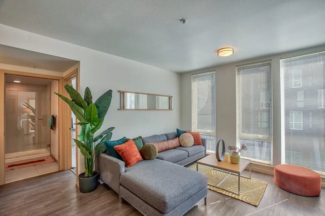 Gray sectional sofa coffee table orange ottoman living room at NOLAN Apartments in Seattle Student Accommodation