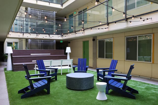 Blue chairs and white bench on grass exterior at NOLAN Apartments in Seattle Student Accommodation