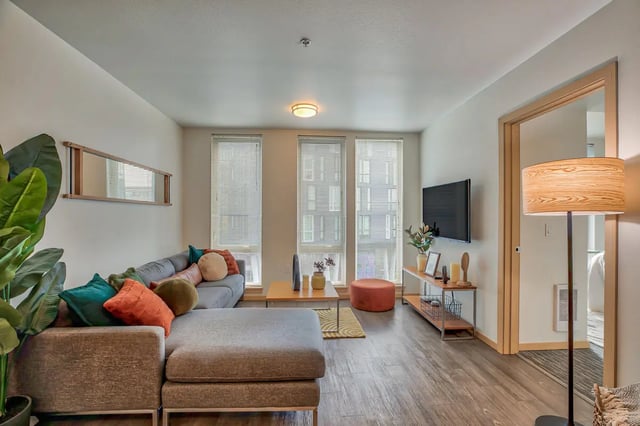 Gray sectional sofa with colorful pillows living room at NOLAN Apartments in Seattle Student Accommodation