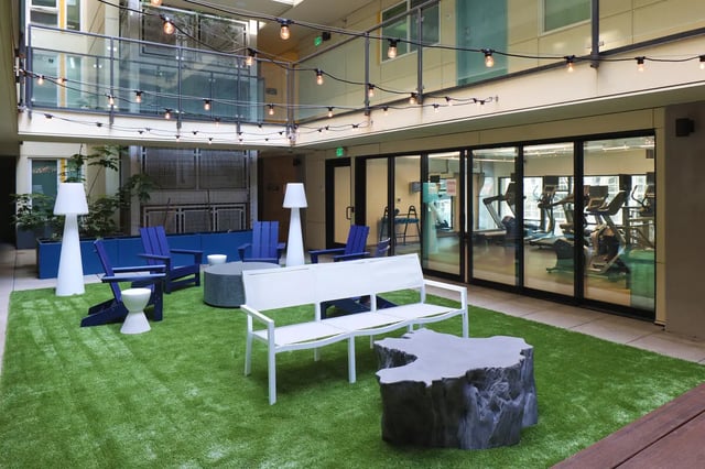 Chairs bench and tables on astroturf patio gym exterior at NOLAN Apartments in Seattle Student Accommodation