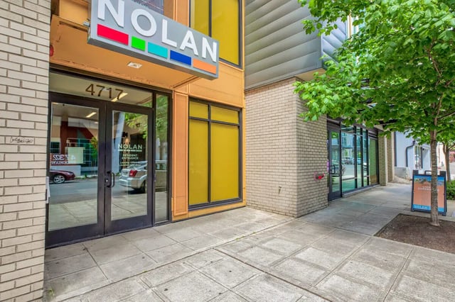 Building entrance with Nolan signage and cars exterior at NOLAN Apartments in Seattle Student Accommodation