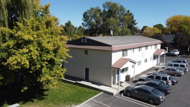 White apartment building with parked cars exterior at Haven White Apartments in Rexburg Student Accommodation