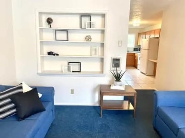 Blue sofas bookshelf kitchen visible living area at Haven White Apartments in Rexburg Student Accommodation