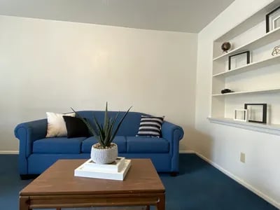 Blue sofa white pillows framed shelves living room at Haven White Apartments in Rexburg Student Accommodation