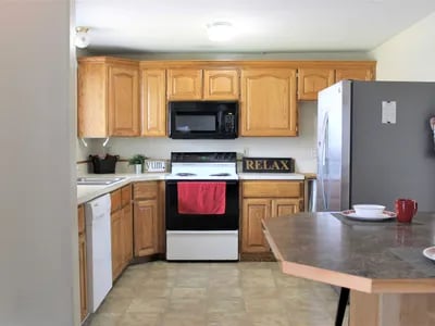 Kitchen with wooden cabinets oven refrigerator and counter. Kitchen at Haven Red Apartments in Rexburg Student Accommodation