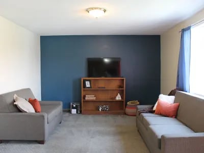 Two sofas bookshelf TV and basket living room at Haven Red Apartments in Rexburg Student Accommodation