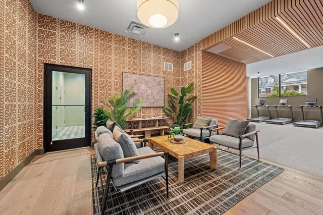 Seating area with treadmills visible beyond living room at Landmark Apartments in College Park Student Accommodation