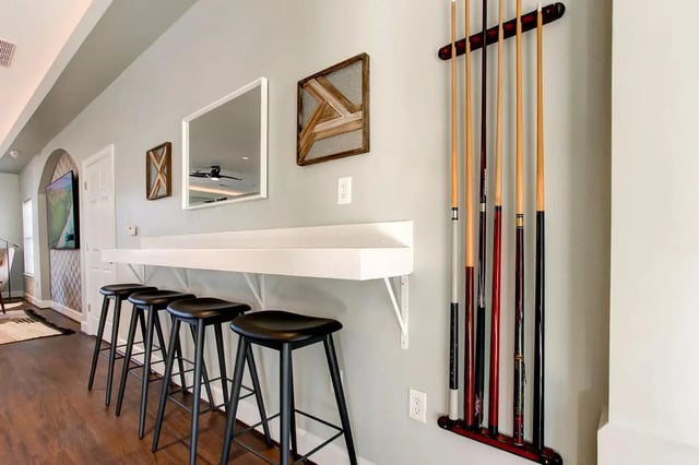 Billiard cues hang above counter with stools living room at Stadium Suites in Columbia Student Accommodation