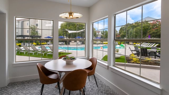 Table with chairs overlooking pool and lounge area. at Maison Burbank in Baton Rouge Student Accommodation
