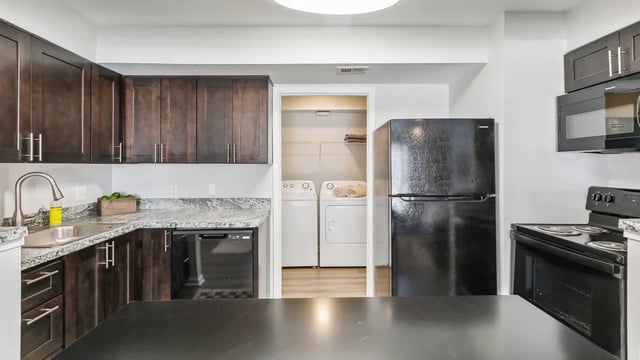 Dark wood cabinets granite counters washer dryer kitchen at Maison Burbank in Baton Rouge Student Accommodation