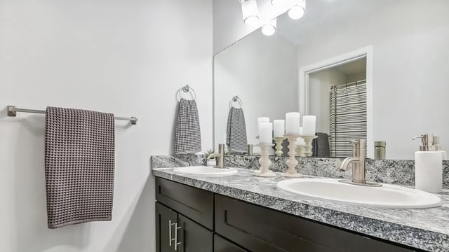 Double vanity with gray countertop and dark cabinets bathroom at Maison Burbank in Baton Rouge Student Accommodation