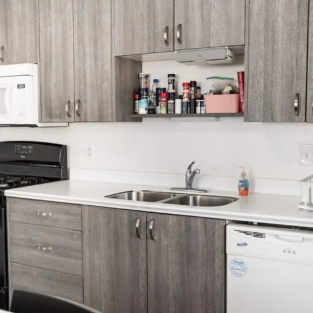Modern grey cabinets sink microwave and dishwasher kitchen at Campus Edge Milledgeville in Milledgeville Student Accommodation