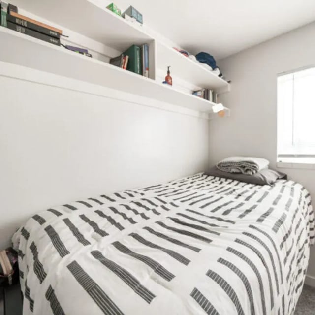 Bed with striped duvet shelves with books Bedroom at Campus Edge Milledgeville in Milledgeville Student Accommodation
