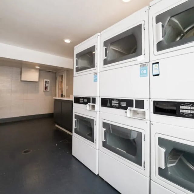 Stacked washers and dryers with dark counter Laundry room at Campus Edge Milledgeville in Milledgeville Student Accommodation