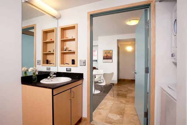 Sink cabinets mirror shelves doorway living room area bathroom at Collegetown Terrace Apartments in Ithaca Student Accommodation