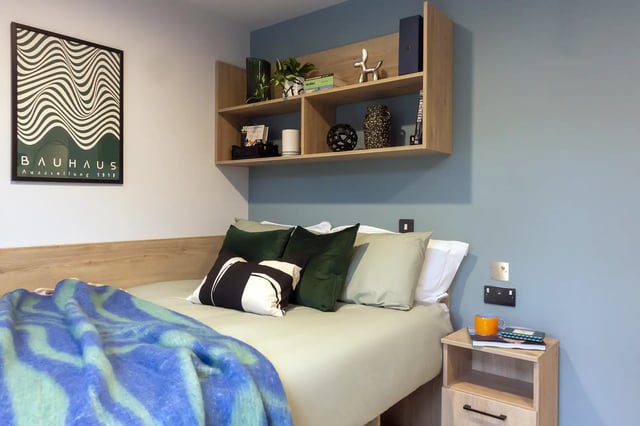 Bed with colorful blanket pillows shelves and poster bedroom at Queen Street Place in Galway Student Accommodation