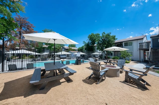 Picnic tables umbrellas fire pit chairs pool exterior at Colony Studios and Apartments in Reno Student Accommodation
