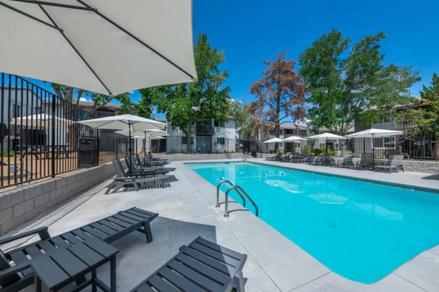Pool lounge chairs umbrellas buildings and trees exterior at Colony Studios and Apartments in Reno Student Accommodation