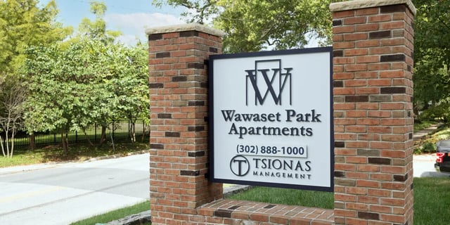 Apartment sign with trees and road exterior at 58 E. Main St. Apartments in Newark Student Accommodation