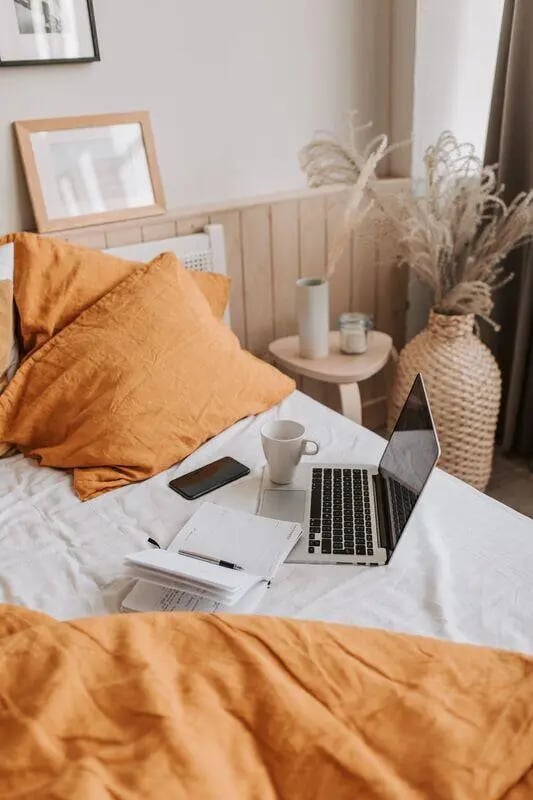 Laptop phone notebook mug on bed Bedroom at Benson Management, Inc. in La Crosse Student Accommodation