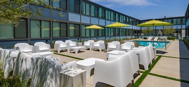 White chairs and tables by pool exterior at Corsica in Los Angeles Student Accommodation
