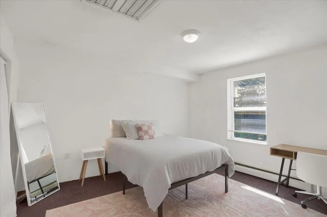 Bed desk mirror and rug bedroom at Cedar Lofts East Apartments in State College Student Accommodation