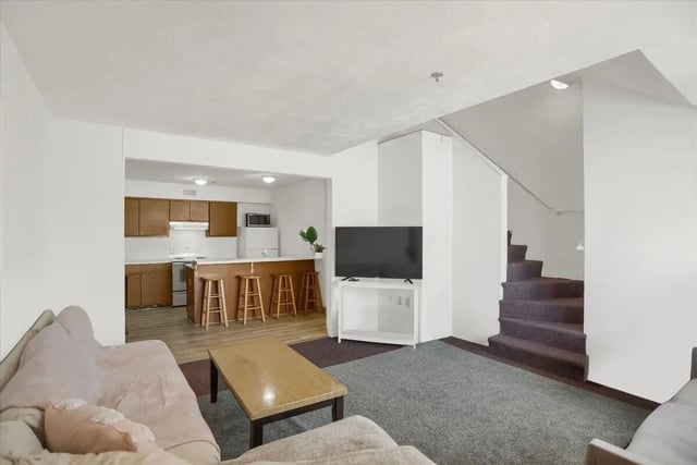Sofa table TV stairs and kitchen living room at Cedar Lofts East Apartments in State College Student Accommodation