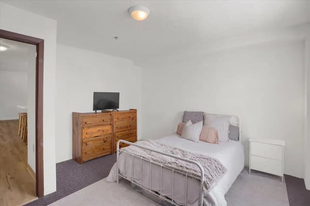 Metal bed frame TV wooden dressers bedroom at Cedar Lofts East Apartments in State College Student Accommodation